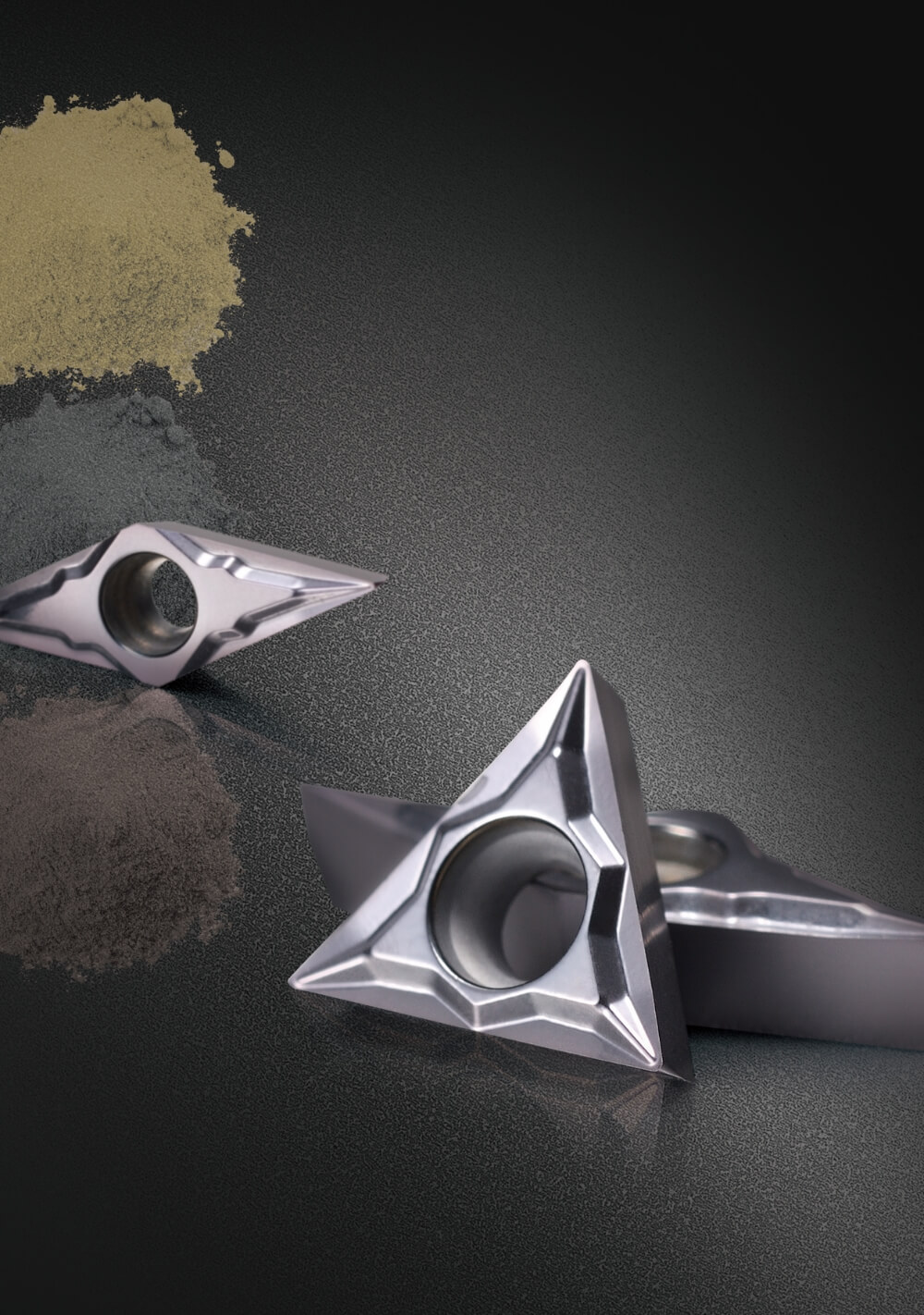 Inserti da taglio triangolari in metallo su sfondo tecnico scuro.